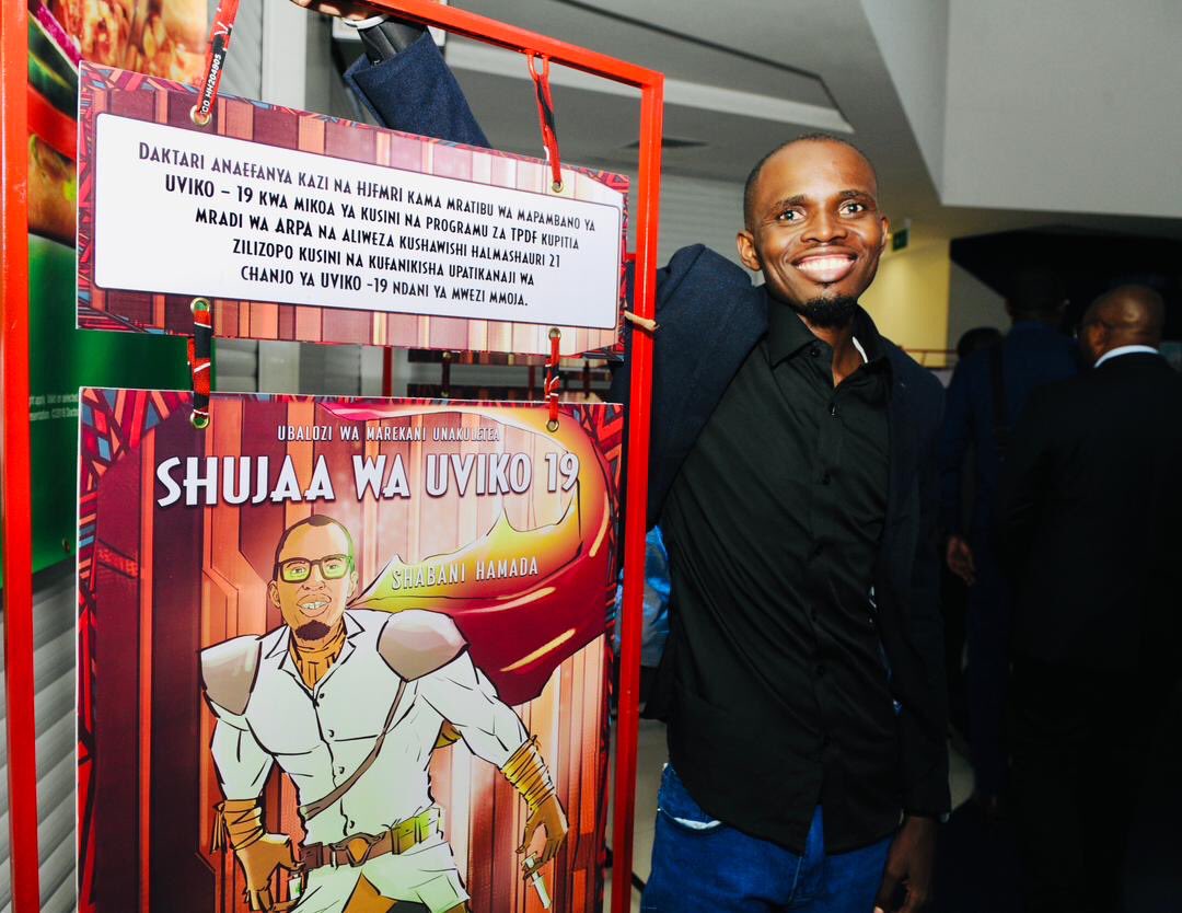 Dr. Shaban stands next to comic book portrait of himself